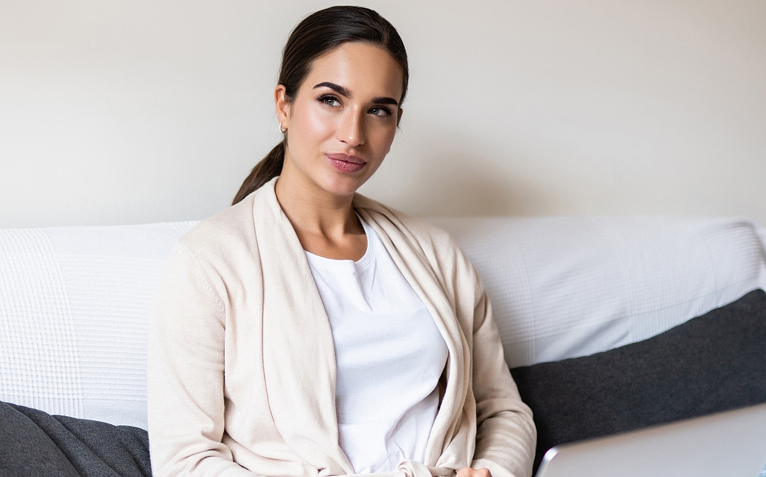 Woman sitting on couch with laptop nearby.
