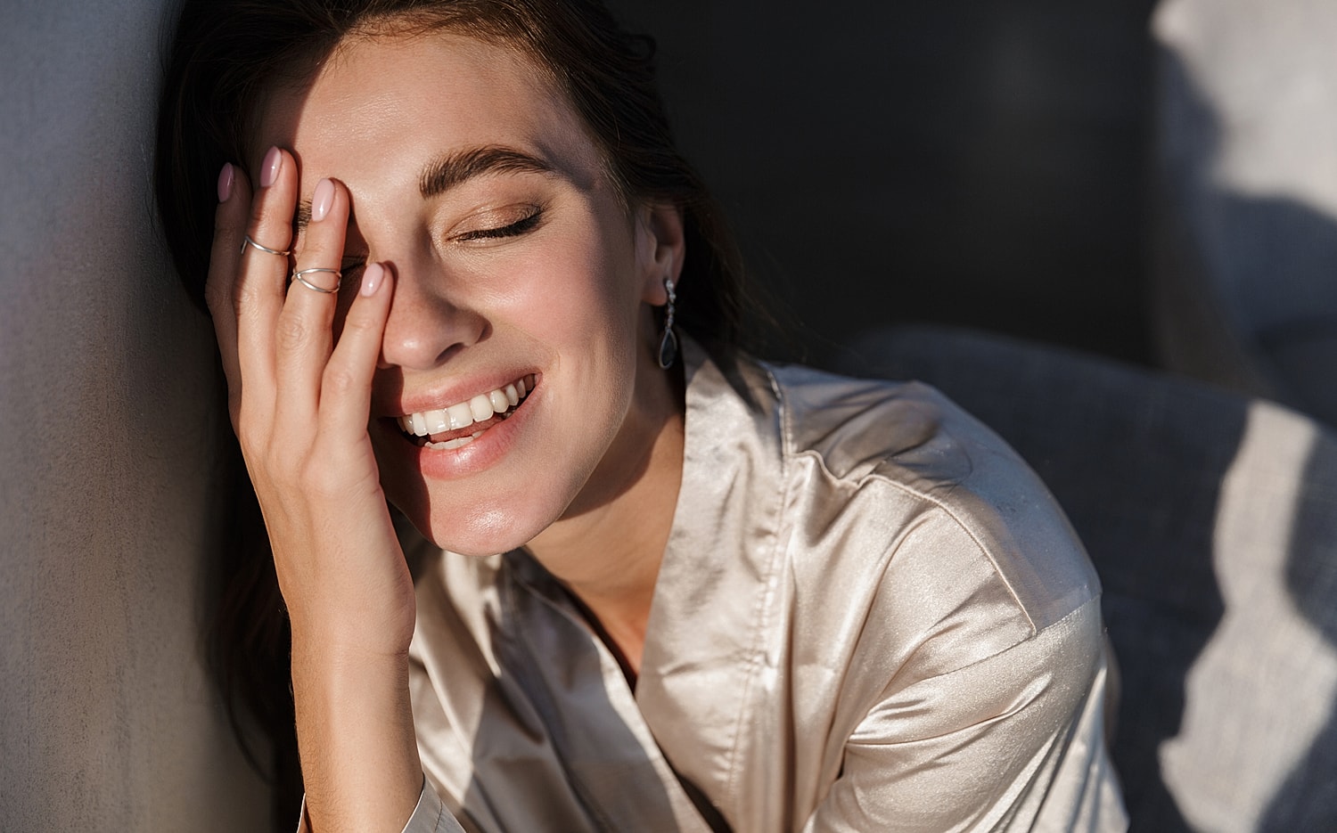 Woman smiling while covering her face joyfully.
