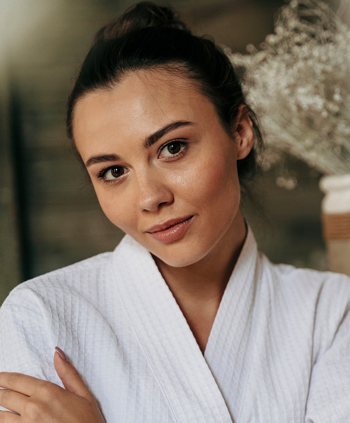 Woman in white robe smiling softly at camera.