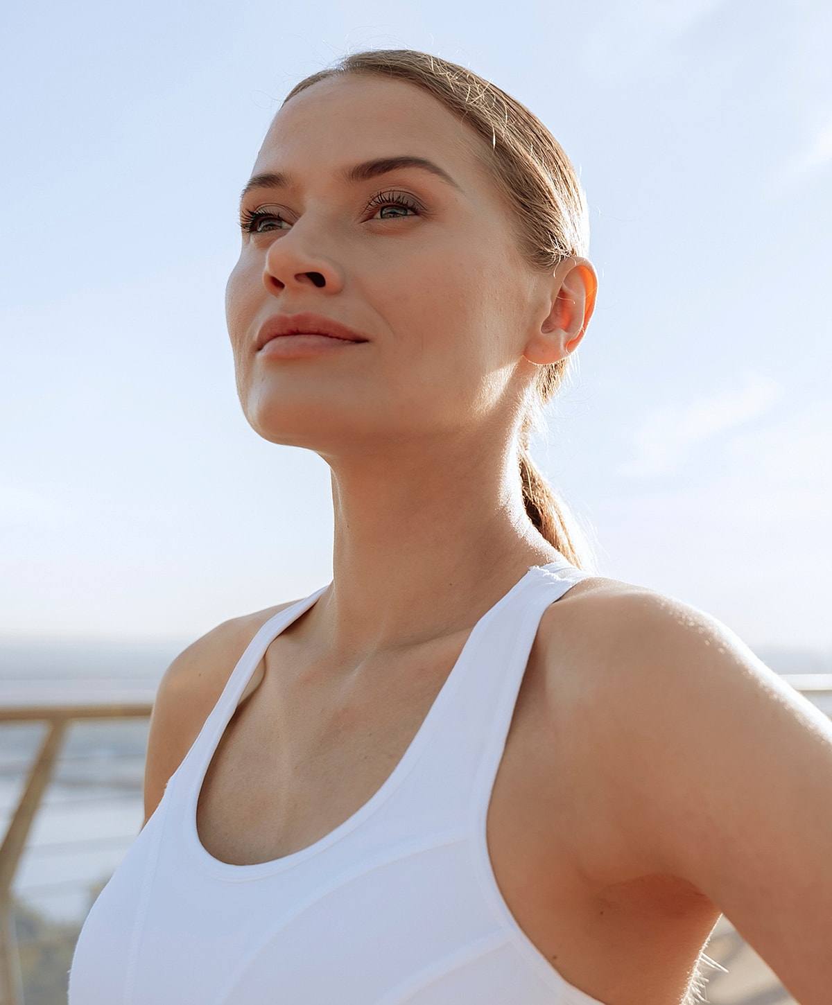 Woman outdoors in athletic attire, looking upwards.