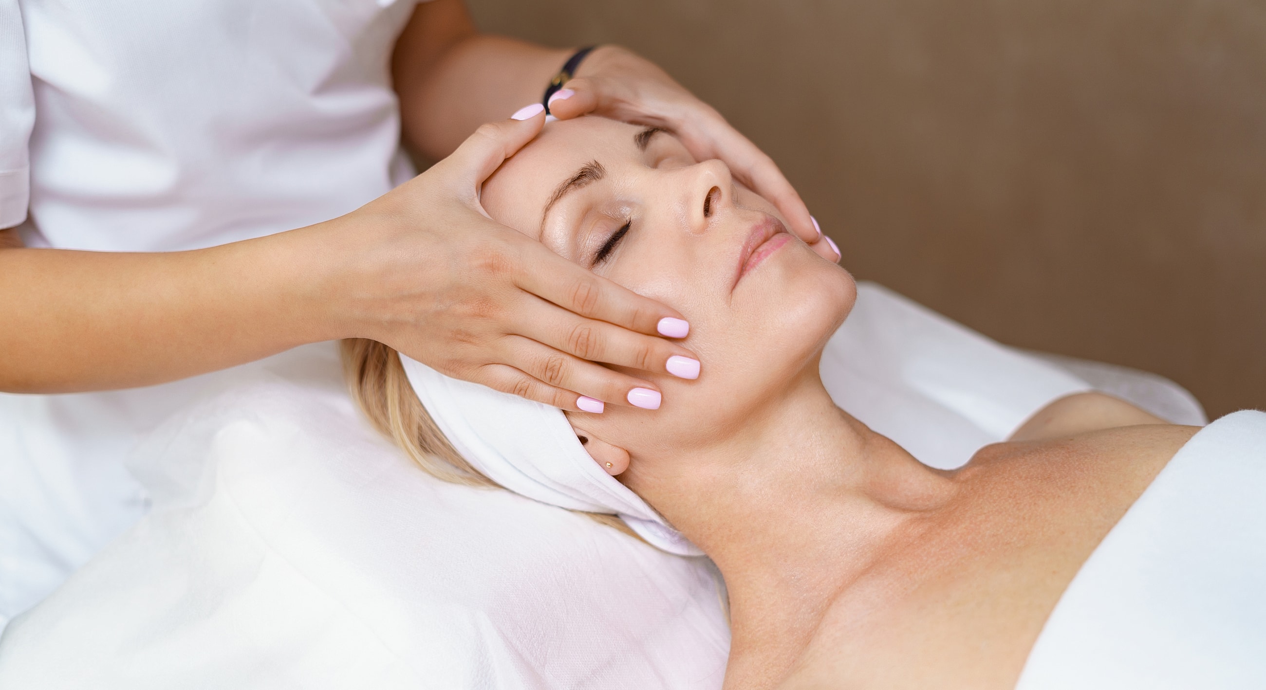Woman receiving a facial massage in spa setting.